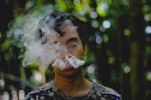 Man with cloud of cigarette smoke wondering if he is addicted to something.