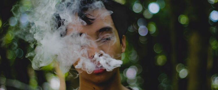 Man with cloud of cigarette smoke wondering if he is addicted to something.