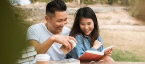 Asian couple reading a book in nature