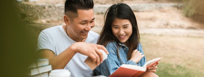 Asian couple reading a book in nature