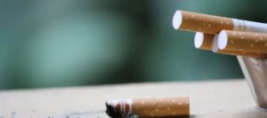 Burnt cigarettes on table against green background.