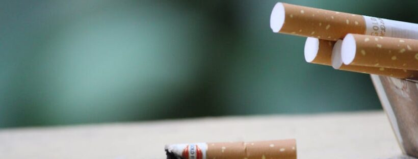 Burnt cigarettes on table against green background.