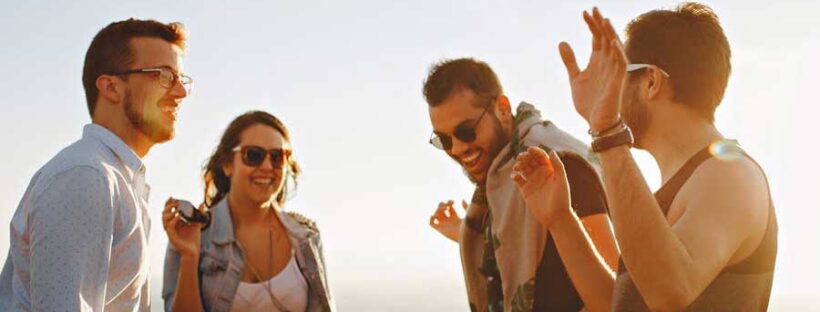 Group of friends at beach laughing while staying sober in Boston, Massachusetts.